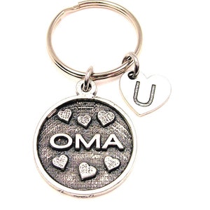 May include: Silver keychain with a round charm that says "OMA" surrounded by small hearts. A smaller heart charm with the letter "U" is attached to the keychain.
