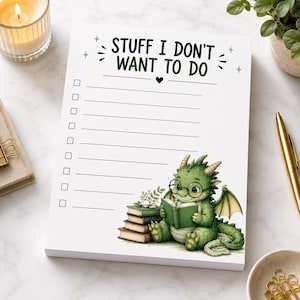 Pode incluir: Um bloco de notas branco com o texto STUFF I DON'T WANT TO DO no topo, apresentando uma lista de caixas de seleção e linhas. Um dragão verde de óculos redondos está ilustrado na parte inferior, sentado e lendo um livro ao lado de uma pilha.