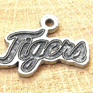May include: Silver charm with the word "Tigers" in a stylized font.