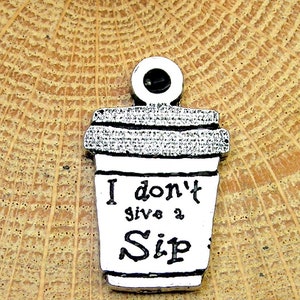 Pode incluir: Encanto de prata em forma de xícara de café com o texto "I don't give a Sip" nele.
