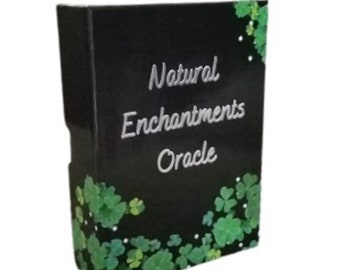 Puede incluir: Caja negra con el texto "Natural Enchantments Oracle" en letras plateadas. La caja está decorada con diseños de trébol de cuatro hojas verdes.