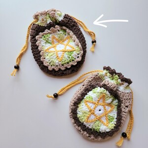 May include: Two crocheted drawstring bags with a star design in shades of brown, green, white, and yellow. The bags have brown wooden beads on the drawstrings.