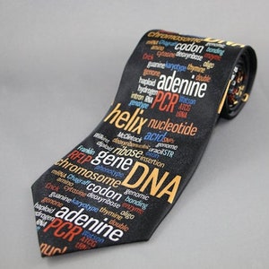 Op de afbeelding: Zwarte stropdas met een herhalend patroon van wetenschappelijke termen zoals "DNA", "helix" en "adenine" in wit, oranje en rood. De stropdas is schuin geplaatst en toont het volledige ontwerp. Een uniek cadeau voor wetenschapsliefhebbers.