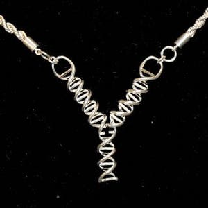 May include: A silver necklace with a double helix DNA pendant. The chain is a twisted rope style.
