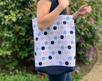 May include: A white tote bag with a polka dot pattern in black, pink, beige, and blue. The bag has a denim bottom.