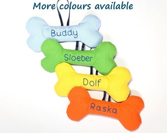 May include: Four colorful dog bone-shaped toys with personalized names: Buddy, Sloeber, Dolf, and Raska. The toys are made of fabric and are hanging from a string.