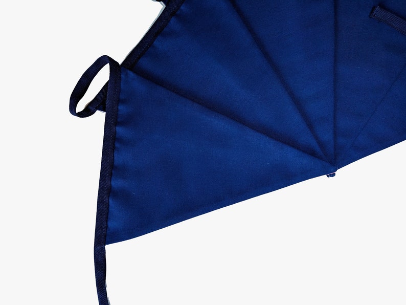 May include: A close-up of a dark blue fabric with a folded edge and a black drawstring. The fabric is folded into a triangular shape.