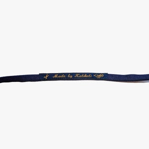 May include: A close-up of a dark blue fabric strap with a gold label that reads "Made by Kalikati".