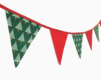 May include: A festive Christmas banner with alternating red and green pennants. The green pennants feature a repeating pattern of white Christmas trees with yellow star toppers. The banner is strung on a red ribbon.