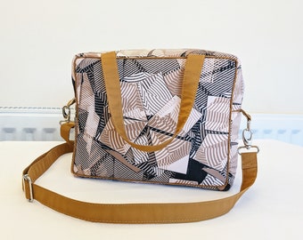 May include: A brown and black geometric patterned tote bag with a brown adjustable shoulder strap.