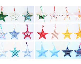 May include: Twenty-four handmade fabric star ornaments in various colors and patterns, including red, green, blue, yellow, and white. The stars are all the same size and shape, and they are hanging from a white background.