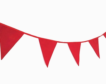 May include: A red fabric bunting with triangular flags strung together. The bunting is hanging from a white background.