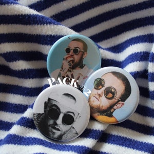 Puede incluir: Tres botones redondos con un retrato de un hombre con gafas de sol. Los botones est&aacute;n sobre un fondo de tela a rayas azules y blancas. El texto "PACK #2" es visible en la imagen.