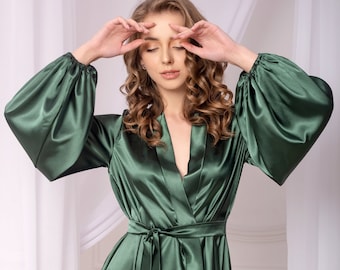 May include: A green satin robe with long sleeves and a tie belt. The robe has a V-neckline and a relaxed fit.