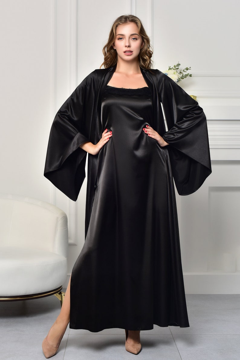 May include: A black satin robe with long sleeves and a matching slip dress. The robe has a wide, flowing silhouette and a deep V-neckline. The slip dress has a simple, elegant design and a straight neckline.