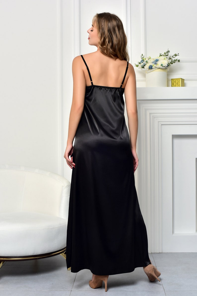 May include: A black satin slip dress with thin straps. The dress is floor length and has a simple, elegant design.