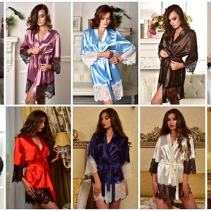 May include: A collection of ten satin robes with lace trim in various colors, including blue, pink, light blue, brown, white, black, red, navy blue, cream, and black. The robes are all knee-length and have long sleeves.