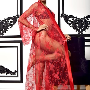 May include: A floor-length red lace robe featuring long, wide sleeves and a smooth satin trim along the front opening. The sheer, intricate floral lace pattern extends from the shoulders to the hem, creating a lightweight, semi-transparent garment.