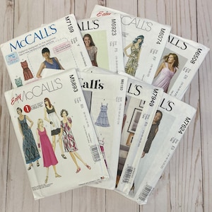 May include: A collection of McCall's sewing patterns, featuring various dress designs. The patterns are in white envelopes with images of the finished garments and model photos. The text includes pattern numbers and size information.