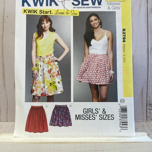 May include: A sewing pattern for a skirt in girls' and misses' sizes. The pattern is from Kwik Sew and is called "Learn-to-Sew". The pattern shows three different skirts, one with a floral print, one with a red and white print, and one with a purple and white print.