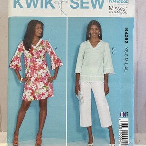 May include: Sewing pattern envelope for a women's top and pants. The pattern is called Kwik Sew K4262 and is for sizes XS-S-M-L-XL. The envelope shows two models wearing the garments. The model on the left is wearing a floral print top with 3/4 sleeves. The model on the right is wearing a light blue top with 3/4 sleeves and white pants.