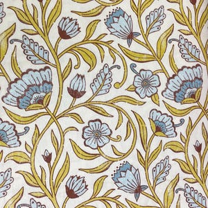 May include: Floral pattern featuring light blue flowers, brown buds, and yellow-green leaves on a cream background. The design has a vintage, botanical aesthetic, with a repeating motif of stylized blossoms and foliage.