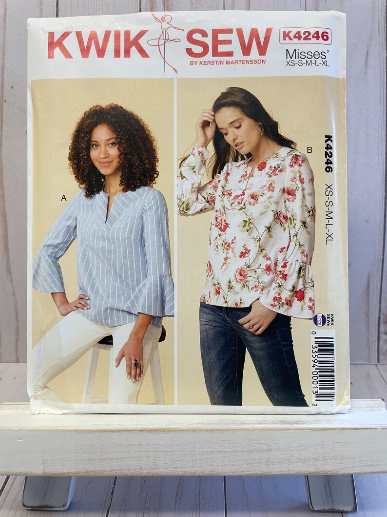 May include: A sewing pattern for a women's blouse with two different styles. The first style is a blue and white striped blouse with a V-neck and 3/4 sleeves. The second style is a white blouse with a floral print and 3/4 sleeves. The pattern is called "Kwik Sew" and the number is K4246. The pattern is for sizes XS-S-M-L-XL.