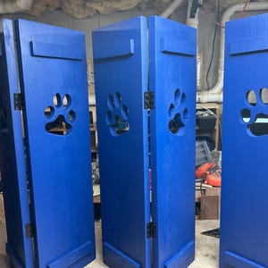 May include: Four blue wooden panels with paw print cutouts. The panels are hinged together and can be folded to create a room divider or privacy screen.