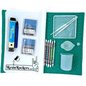 May include: A green silicone mat with a honeycomb pattern, a white measuring cup, a white square dish, two white tools, five glitter-covered tools, two packs of small metal tools, a blue deburring tool, a blue tool, and a white sheet with the text "ResinRockers.com" and a hand with a rock and roll hand gesture.