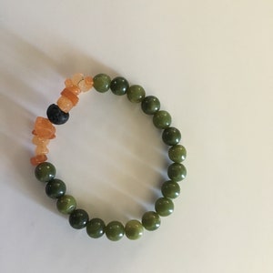 May include: A green jade beaded bracelet with orange and brown carnelian beads and a black lava bead.