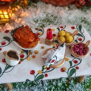 Könnte beinhalten: Ein Miniatur-Weihnachts-Esstisch mit einem Brathähnchen, einer Soßenschüssel, Kartoffeln, Rotkohl, einer Serviette und einer Kerze.