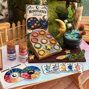 Könnte beinhalten: Eine detaillierte Miniatur-Fantasieszene mit einer Palette bunter Farben, Pulvergläsern und einem kleinen Kessel, mit Mond- und Sternakzenten. Die Szene enthält den Text "Mondfarben" und Farbkarten.