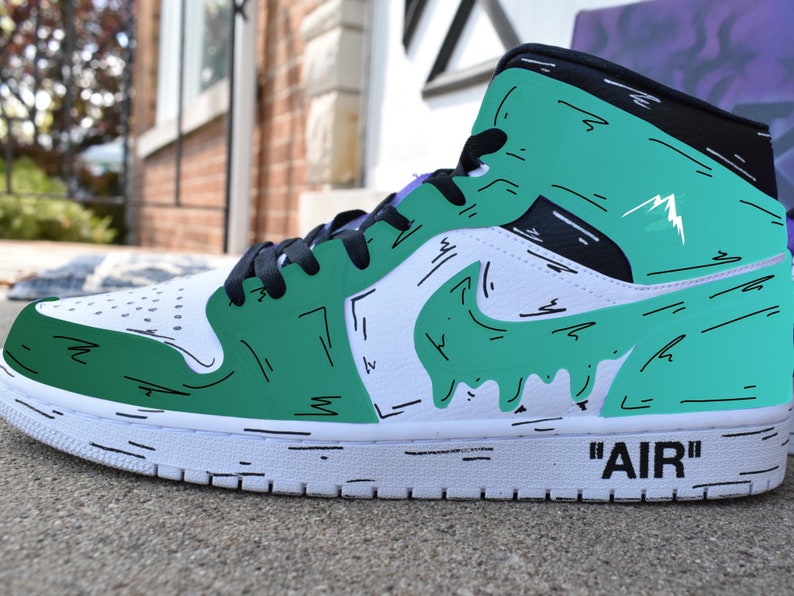 May include: White and green high-top sneakers with black accents and a black and white 'AIR' logo on the side. The sneakers have a green and white paint design with black outlines.