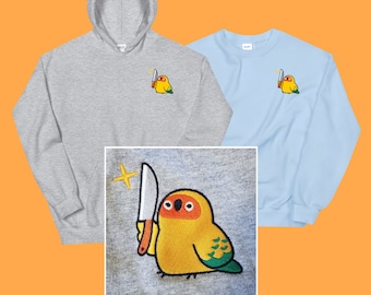 May include: Two sweatshirts with embroidered images of a yellow and green bird holding a knife. One sweatshirt is gray and the other is light blue.
