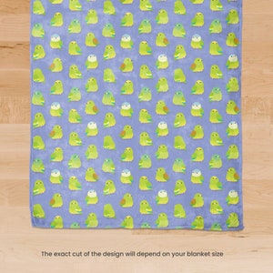 May include: A soft, light blue blanket featuring a repeating pattern of cartoon parakeets in shades of green, yellow, and white. The parakeets are arranged in a grid-like fashion across the blanket's surface. The text at the bottom says, "The exact cut of the design will depend on your blanket size."