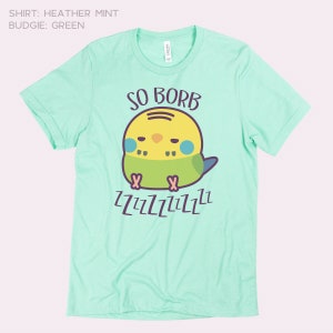 May include: A light green t-shirt featuring a cartoon green and yellow budgie. The budgie is sleeping and the text "SO BORB" is above it. The text "ZZZZZZZZZZ" is below the budgie.