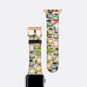 May include: A watch band with a repeating pattern of colorful cartoon parrots. The band is made of a light beige material with gold-colored hardware. The parrots are green, red, blue, and yellow.