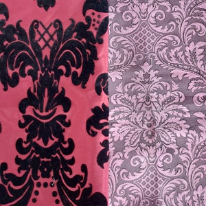 May include: Two fabric swatches with a damask pattern. The left swatch is red with a black pattern. The right swatch is pink with a gray pattern. The word "burlesque" is written above the swatches. The word "red" is written below the left swatch and the word "pink" is written below the right swatch.