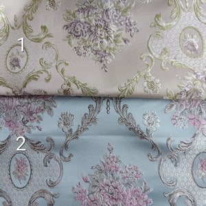 May include: Two fabric swatches with a baroque floral pattern. The top swatch is a light pink color with a green and purple floral design. The bottom swatch is a light blue color with a green and pink floral design.
