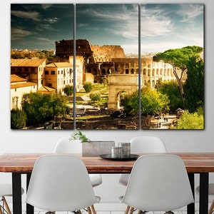 May include: A three-panel canvas print featuring a panoramic view of the Colosseum in Rome, Italy. The image shows the ancient Roman amphitheater, with its iconic arches and walls, surrounded by lush greenery and a clear blue sky.