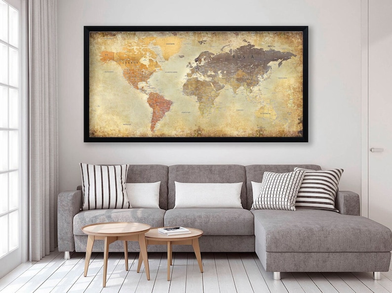 May include: A vintage-style world map print in a black frame hangs above a gray sectional sofa with white and black striped throw pillows. The map has a distressed, aged look with a beige background and brown and orange continents.