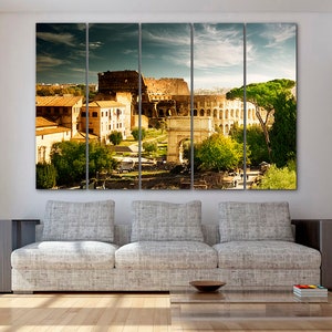 May include: A panoramic view of the Colosseum in Rome, Italy. The ancient Roman amphitheater is surrounded by trees and buildings. The sky is blue with white clouds.