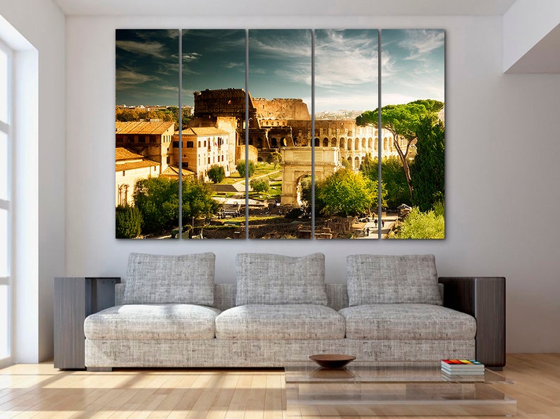 May include: A panoramic view of the Colosseum in Rome, Italy. The ancient Roman amphitheater is surrounded by trees and buildings. The sky is blue with white clouds.