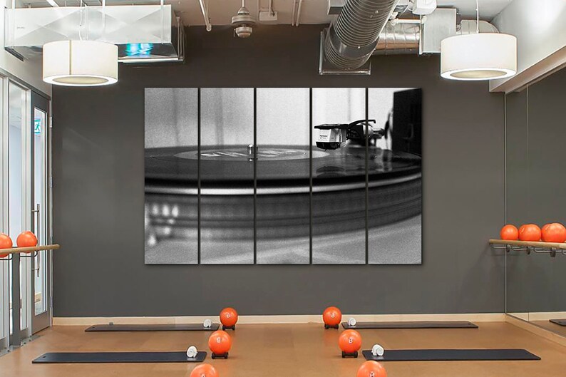 Puede incluir: Una fotograf&iacute;a en blanco y negro de un tocadiscos con un disco girando en el plato. La foto est&aacute; dividida en cinco paneles y se muestra en una pared en una habitaci&oacute;n con pelotas de ejercicio naranjas y esteras de yoga.