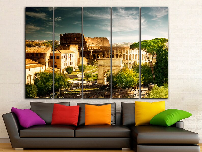 May include: A multi-panel canvas print featuring a panoramic view of the Colosseum in Rome, Italy. The image shows the ancient amphitheater, surrounded by trees and buildings, with a clear blue sky in the background.