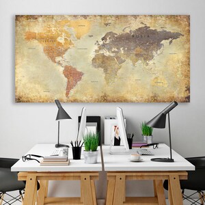 May include: A vintage-style world map print with a distressed, aged look hangs above two white desks with black chairs. Each desk has a black lamp, a computer monitor, and a potted plant.