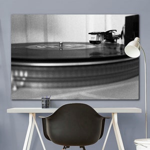 Puede incluir: Una fotograf&iacute;a en blanco y negro de un tocadiscos con un disco girando en el plato. La aguja est&aacute; en el surco del disco y el brazo de lectura est&aacute; extendido.