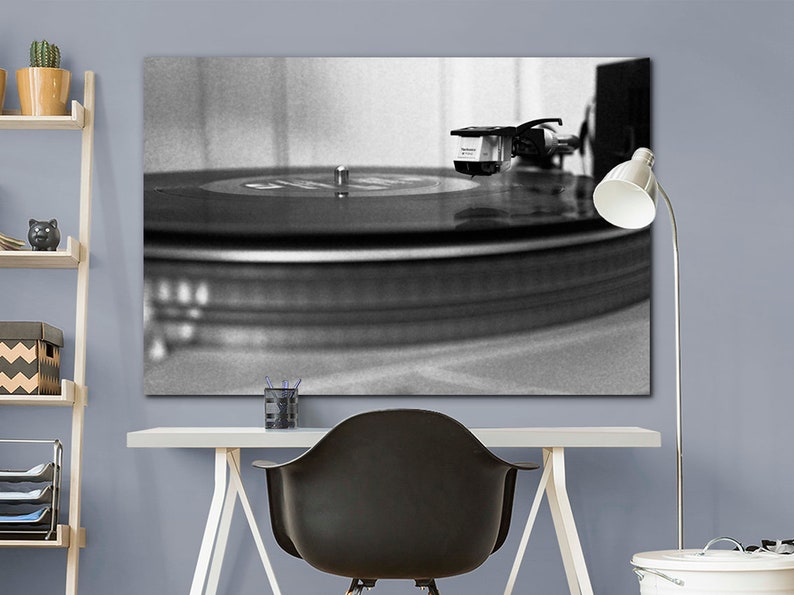 Puede incluir: Una fotograf&iacute;a en blanco y negro de un tocadiscos con un disco girando en el plato. La aguja est&aacute; en el surco del disco y el brazo de lectura est&aacute; extendido.