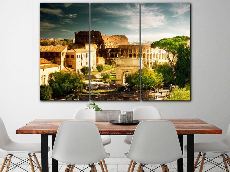 May include: A three-panel canvas print featuring a panoramic view of the Colosseum in Rome, Italy. The image shows the ancient Roman amphitheater, with its iconic arches and walls, surrounded by lush greenery and a clear blue sky.