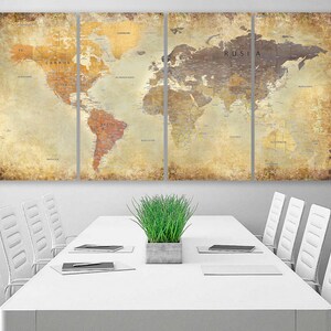 May include: A vintage-style world map print in four panels, featuring a distressed, aged look. The map is displayed on a white wall above a white conference table with white chairs and a potted green plant.